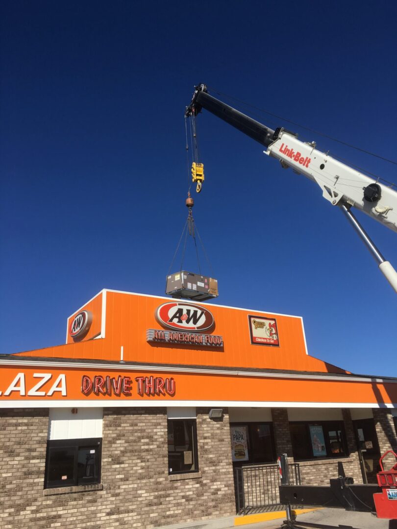 Crane lifting HVAC unit onto A&W restaurant roof