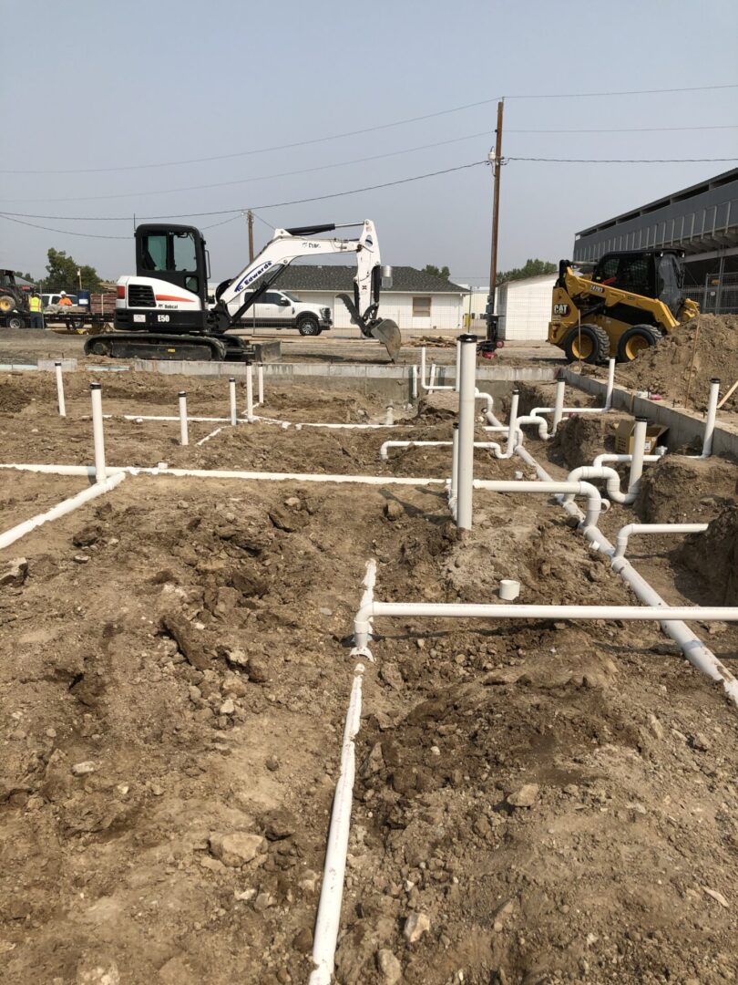 Excavators at foundation with exposed plumbing pipes
