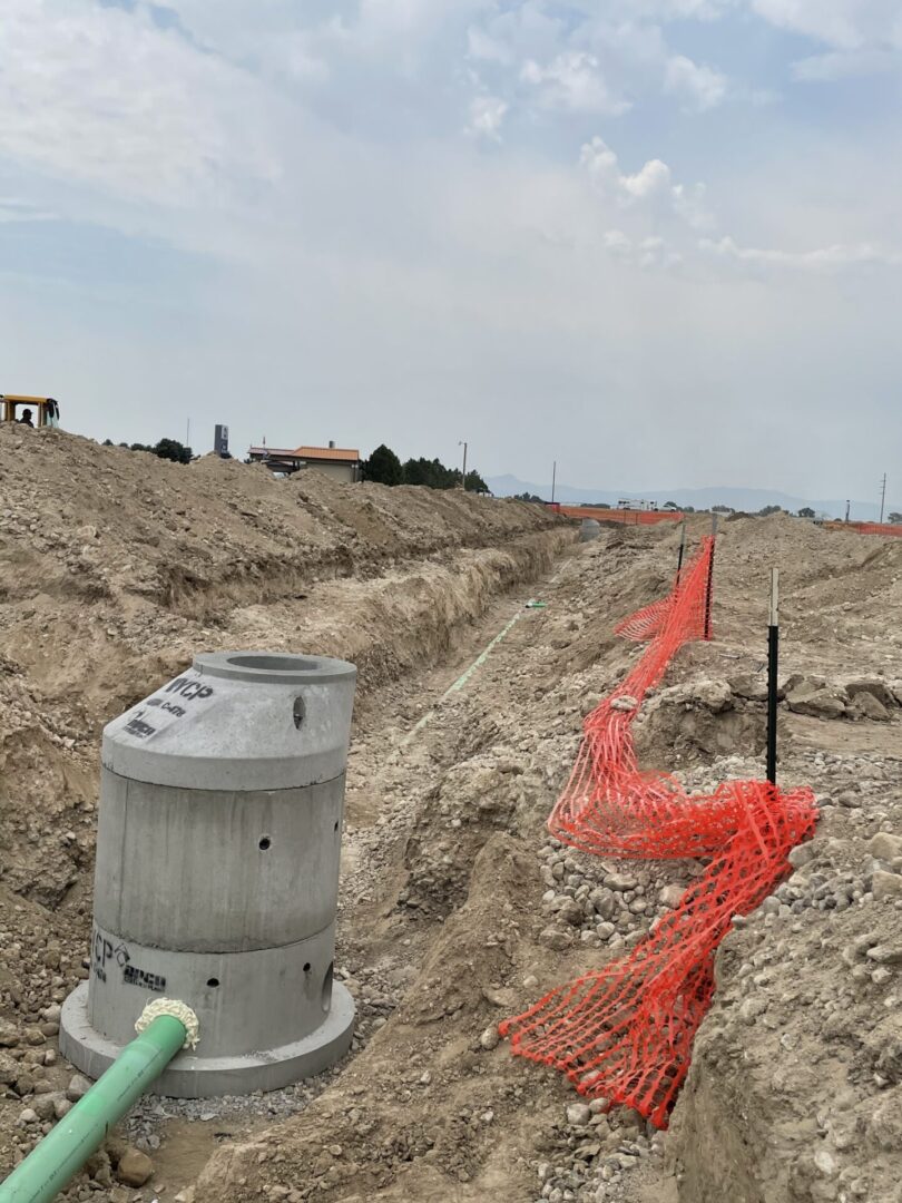 Trench with sewer pipe and orange safety fencing